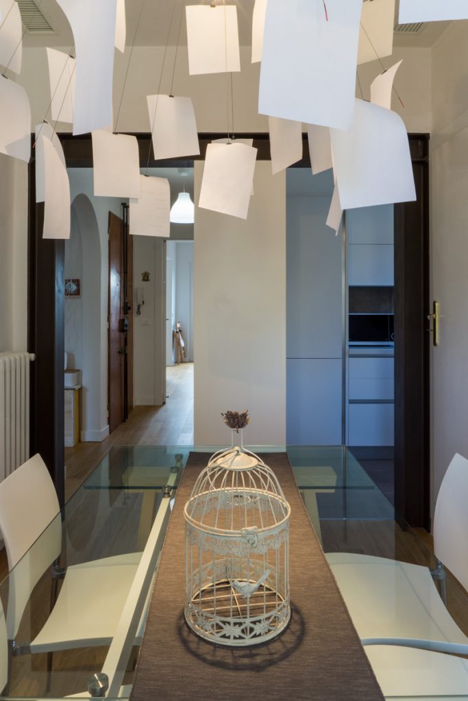 Casa AJ - Dettaglio del tavolo in vetro con sedie in acciaio e ABS della zona pranzo e vista sulla zona cottura - Tommaso Vecci