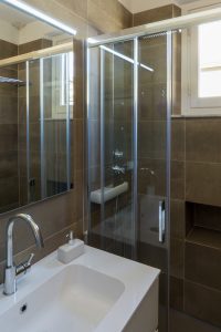 Casa AJ - Dettaglio del lavabo e della doccia, con porta scorrevole in cristallo e colonna idromassaggio - Tommaso Vecci